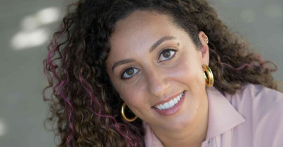 Headshot of Rabbi Tarlan Rabizadeh in a purple shirt, gold earrings, and purple streaks in her hair