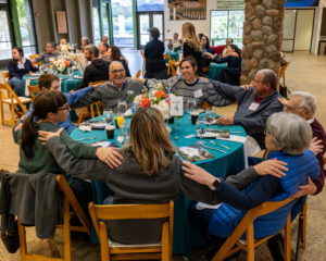 People smiling at an Alonim event with their arms linked around a table