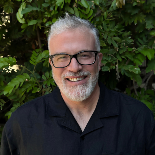Headshot of John Carrier in glasses and a black shirt