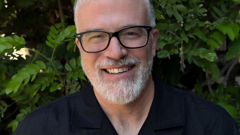 Headshot of John Carrier in glasses and a black shirt