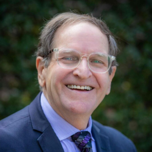 Headshot of Ron Wolfson in glasses, a blue shirt, blue jacket , and tie
