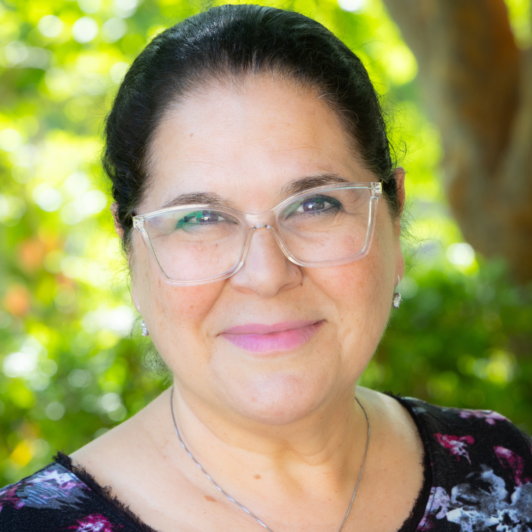 Headshot of Rachel Raz in clear glasses and a blue and purple shirt
