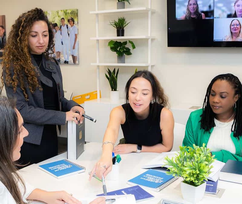 A teacher in class leading a group of 3 visible students at the Maas Center