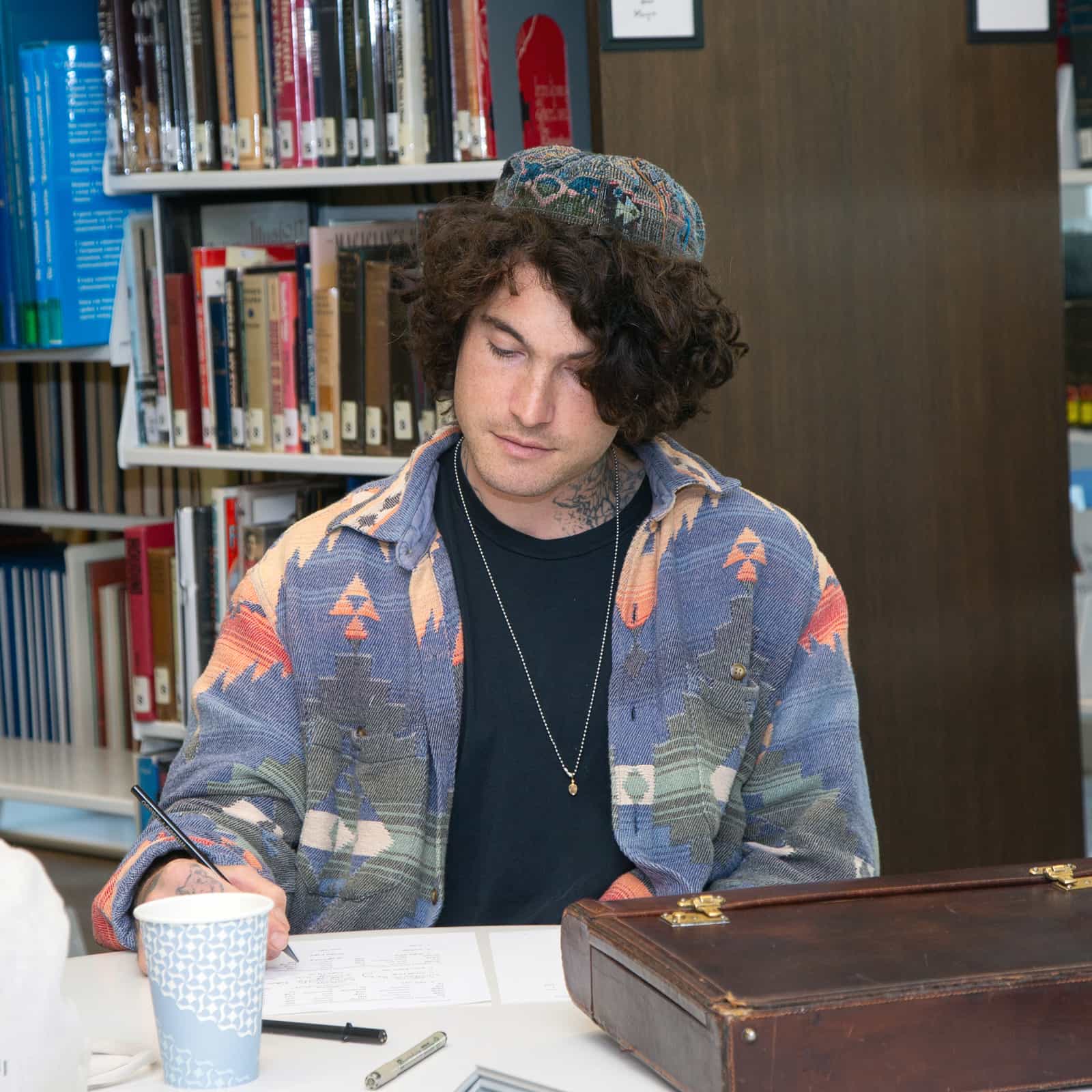 Rabbinical student studying and writing at a desk in a library at the Ziegler School of Rabbinical Studies.