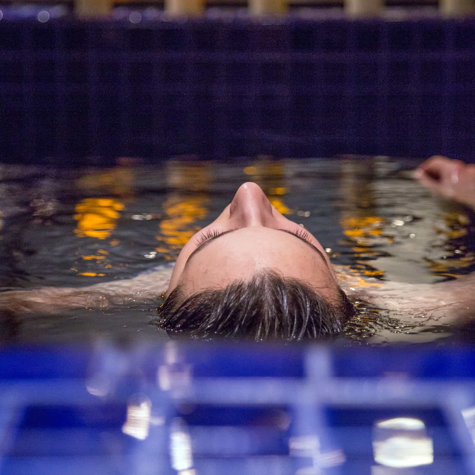 Woman floating in a mikvah during a Jewish ritual immersion, reflecting a moment of renewal and spiritual connection.
