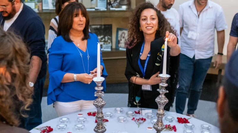 Participants gathered around a table lighting candles during a Jewish learning experience at the Maas Center.