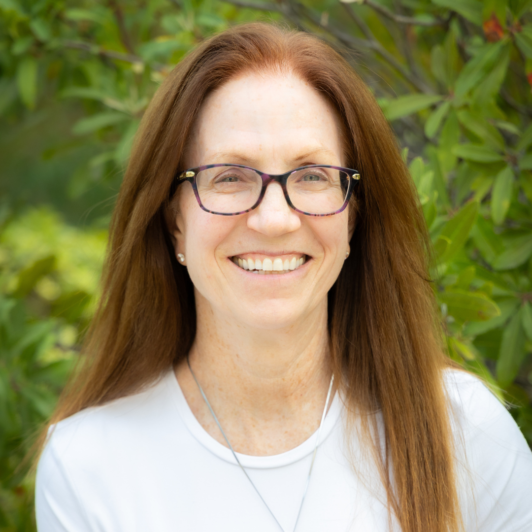Headshot of Dr. Tamar Andrews in black glasses and a white shirt