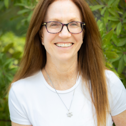headshot of Tamar Andrews in a white shirt glasses and a maagan david