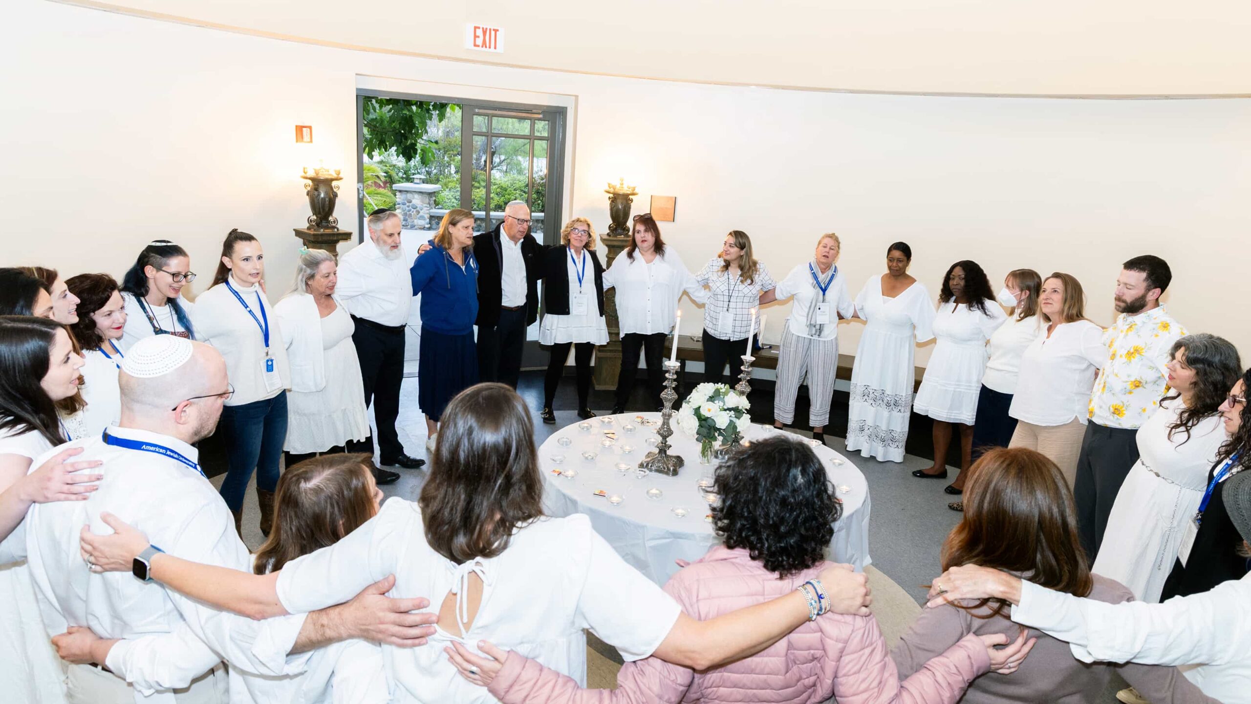 Participants standing in a circle with arms around each other during a shared community moment at the Masor School for Jewish Education & Leadership.