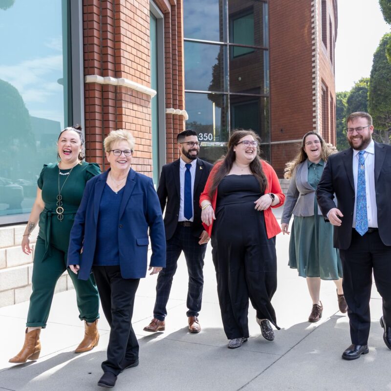 A photo of rabbis outside of the Ziegler School, walking and smiling at each other.