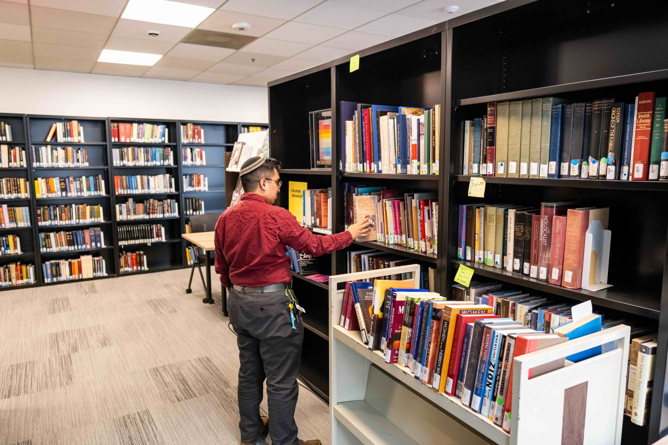 A librarian putting books back on a shelf in the library.