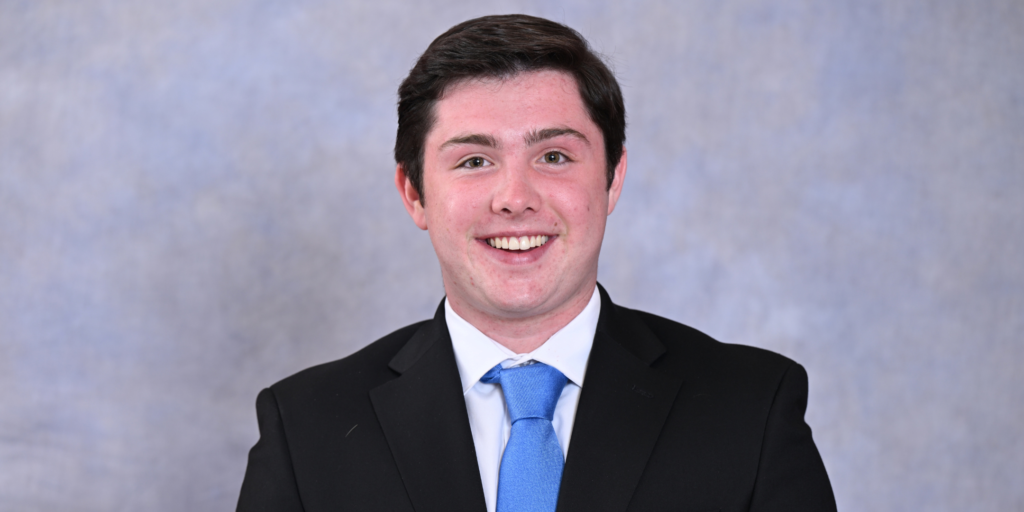 Matthew Devaney, 19, in a black jacket and white shirt and color with a blue tie