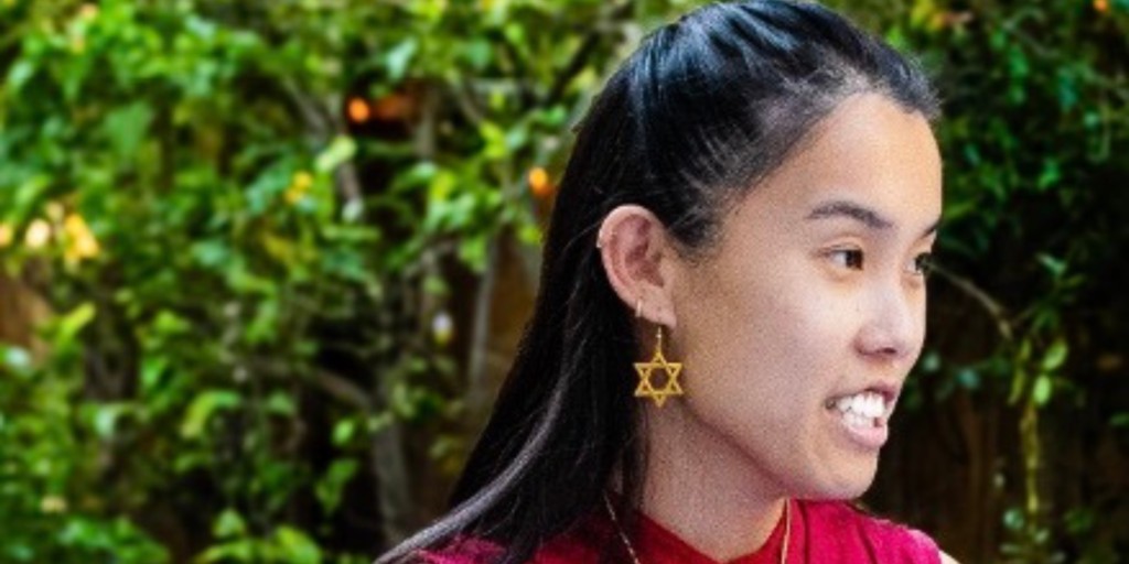 A side profile of Vanessa Bloom wearing a red shirt and a gold Jewish star earring
