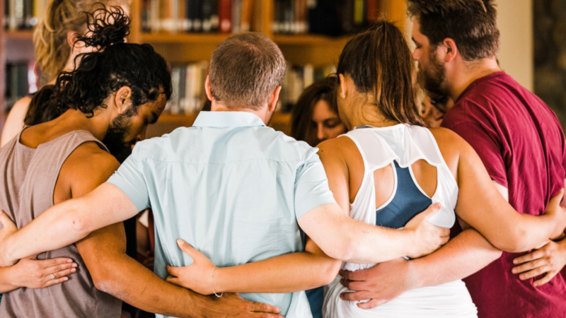 A group of young people standing in a circle with their arms around each other