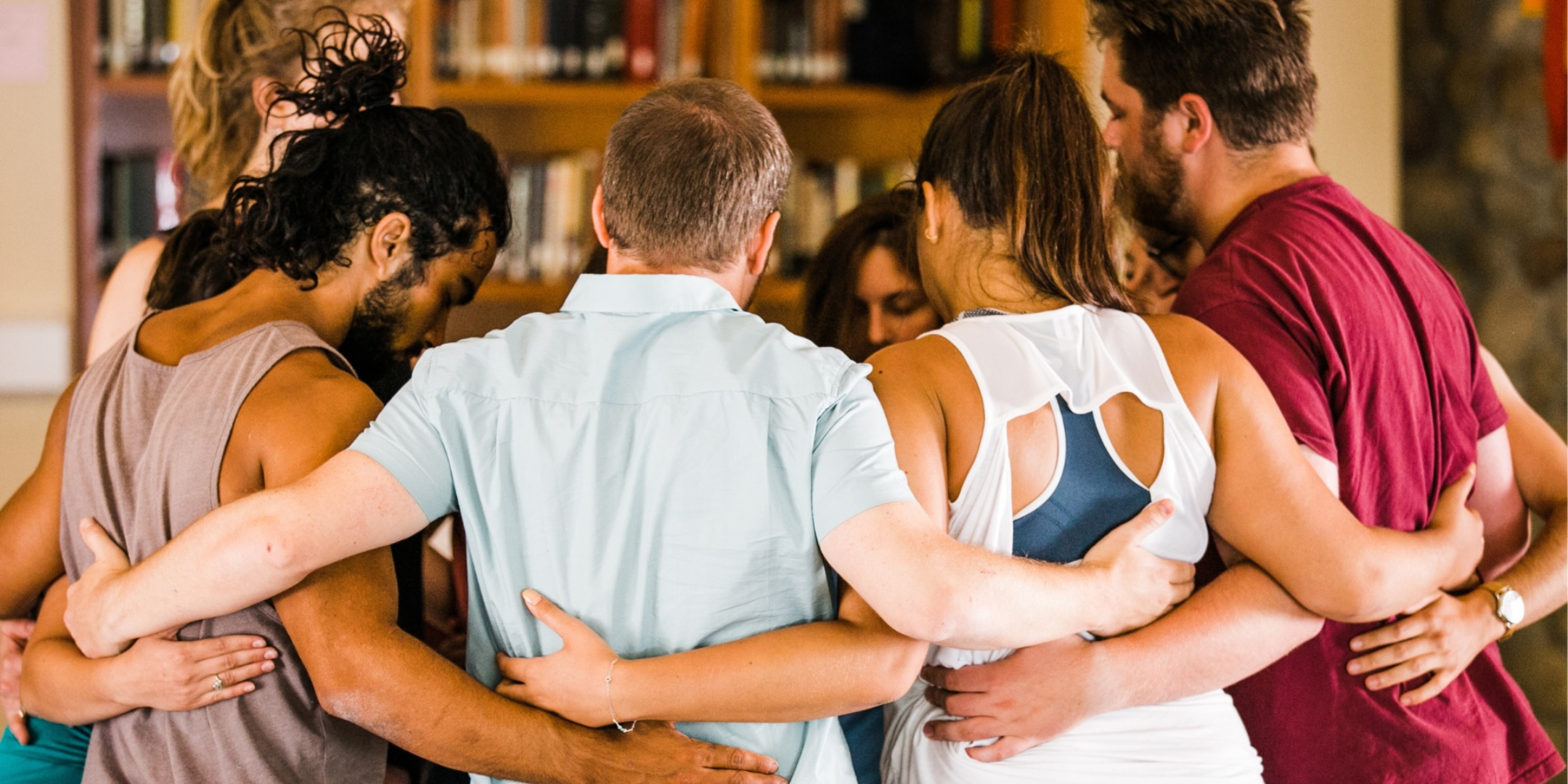 A group of young people standing in a circle with their arms around each other