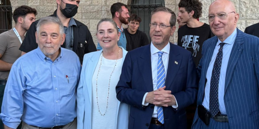 Michael Berenbaum in a blue shirt standing next to a woman standing next to two men in blazers
