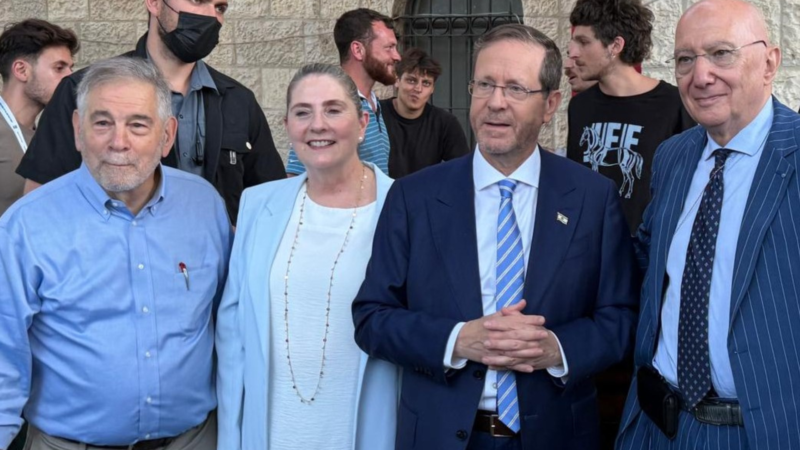 Michael Berenbaum in a blue shirt standing next to a woman standing next to two men in blazers