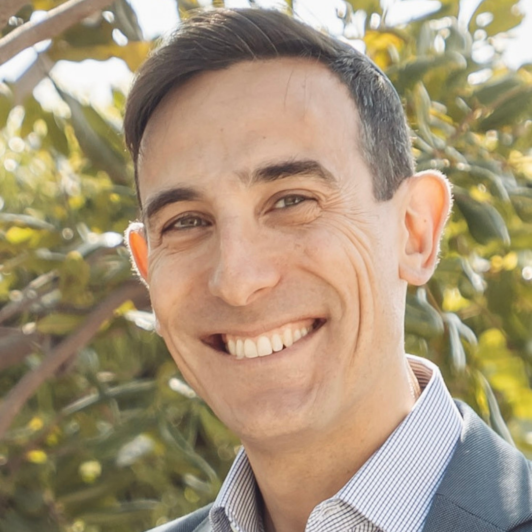 Rabbi Ephraim Pelcovits smiling in a blue collared shirt