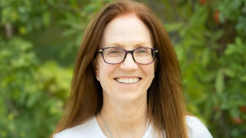 Tamar Andrews smiling at the camera in a white top and glasses