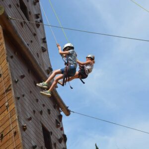 Camper rappel down a tall rock climbing wall