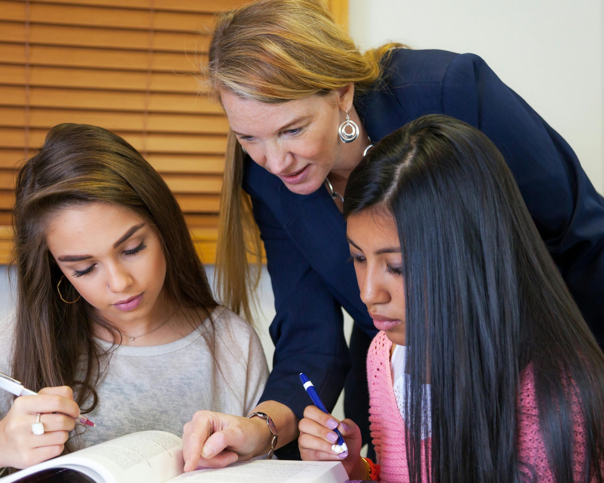 An instructor helps 2 teen students